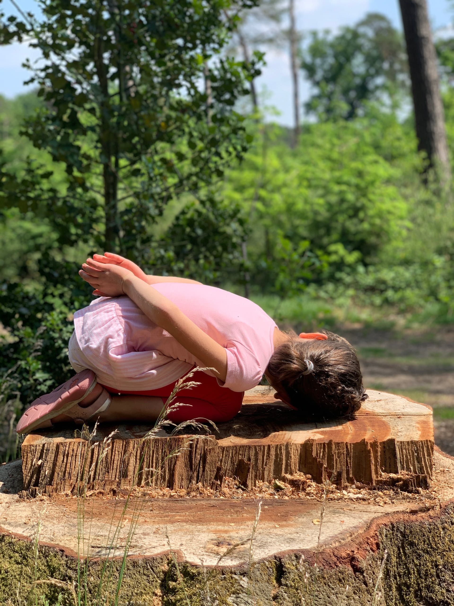 Kind in einer ruhigen Yoga-Haltung im Grünen