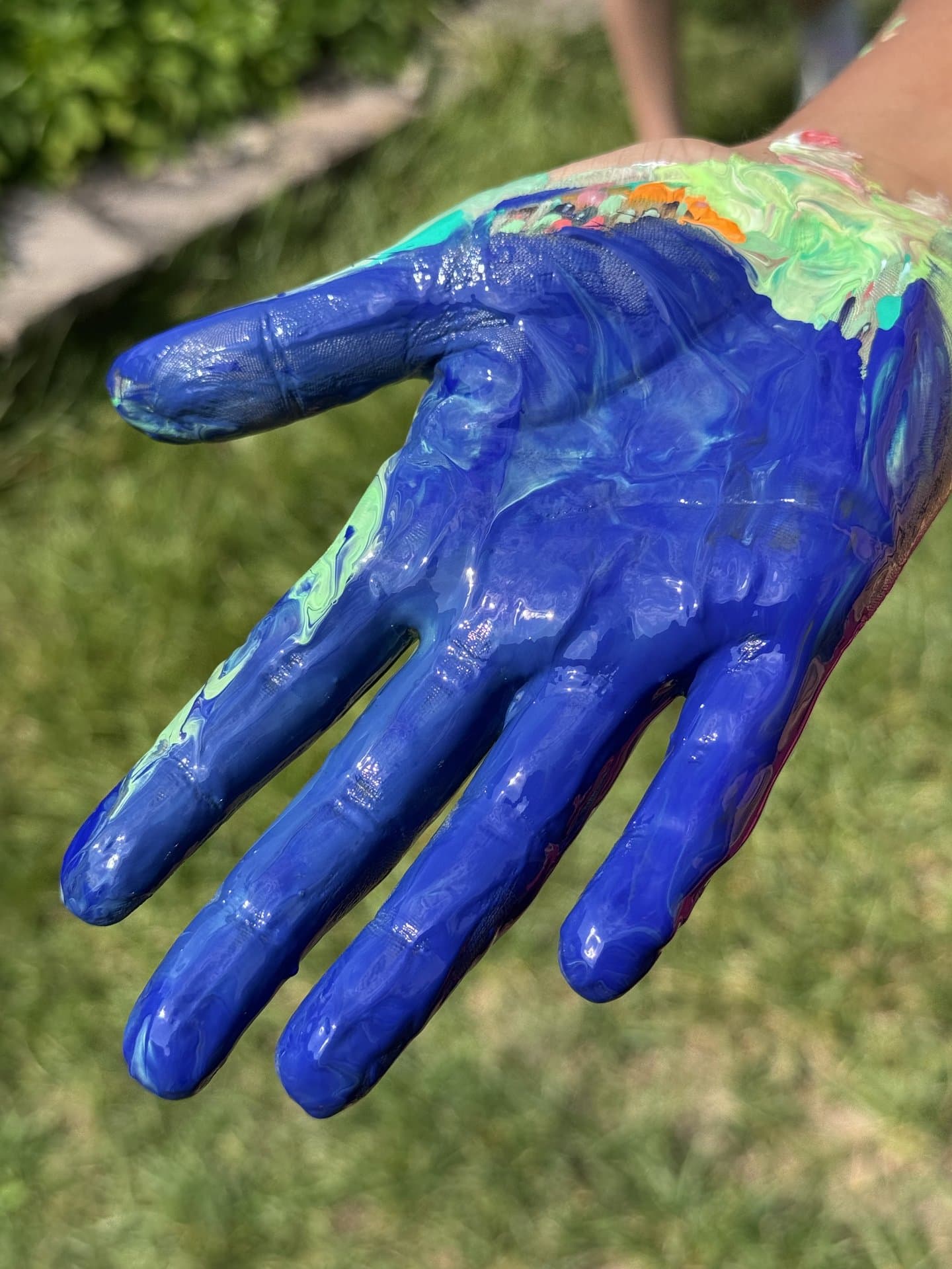Bunt bemalte Kinderhand von der Kreativzeit im Freien