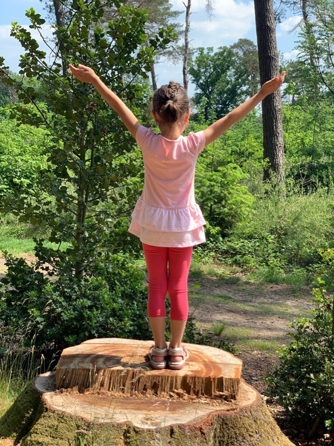 Kind macht Yoga auf einem Baumstamm