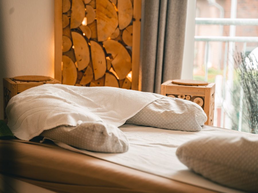 Gemütliche Liege mit weißen Kissen und Decke am Fenster