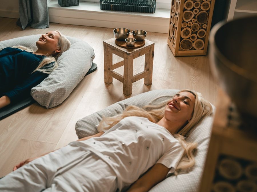 Zwei Frauen liegen entspannt bei einer Klangreise auf Matten