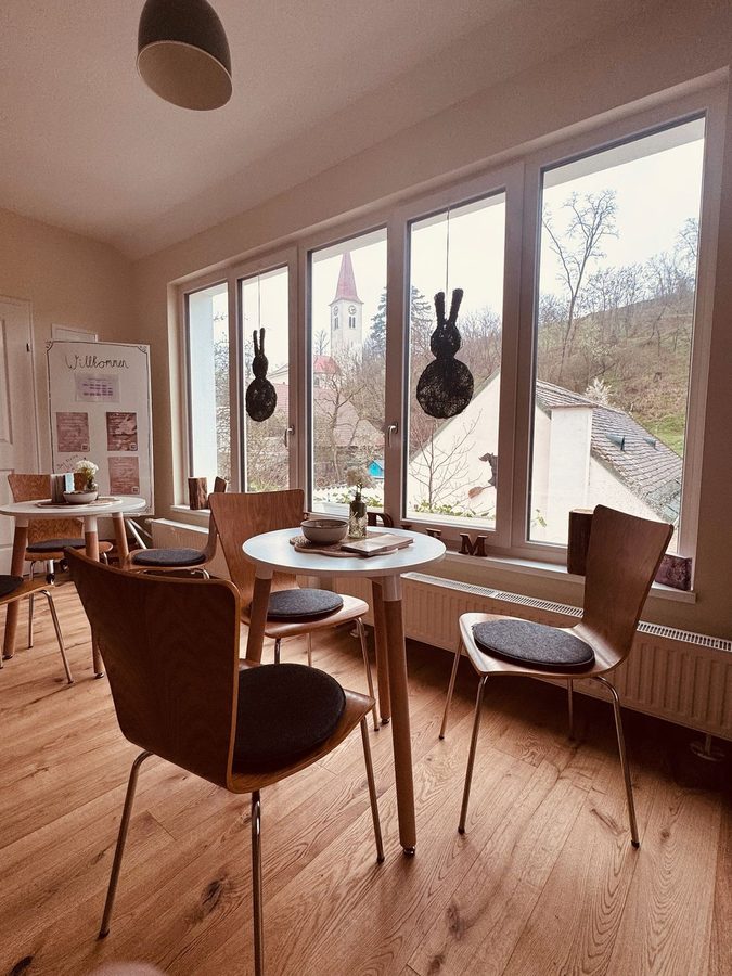 Freundlicher Aufenthaltsraum mit Bistrotischen und Willkommens-Aufsteller