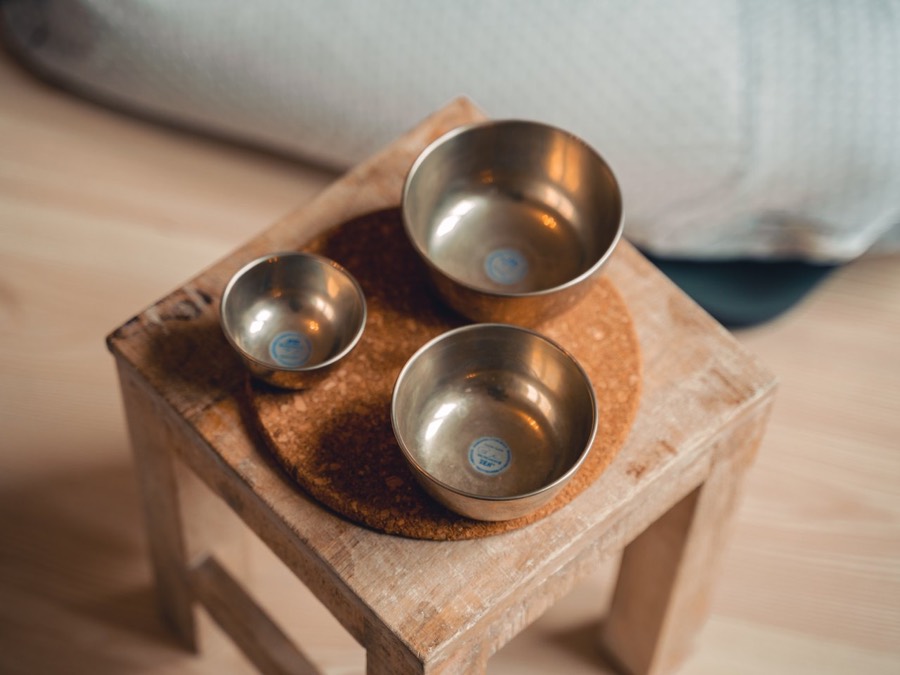 Klangschalen auf einem Holztisch im warmen Licht des Wohlfühlraums